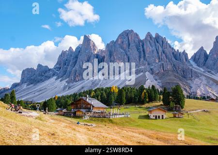 Maestoso paesaggio dolomitico caratterizzato da capanne rustiche e vette torreggianti alla luce del sole autunnale Foto Stock