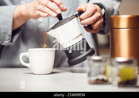 Preparazione di una tazza di caffè fresco con classica moka italiana in cucina moderna Foto Stock