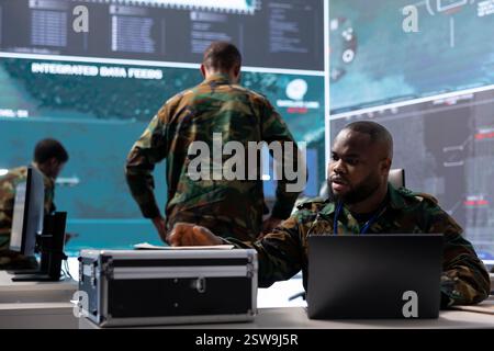 Esperto militare studia vecchi documenti classificati in una base di potere di una torre di controllo, raccogliendo informazioni dai sistemi satellitari e dalle missioni passate. Elaborare le informazioni critiche e la pianificazione strategica. Foto Stock