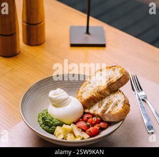 Deliziosa insalata di burrata servita sul tavolo del ristorante con fette di pane tostato Foto Stock