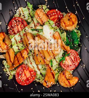 Insalata di pesce fresca e sana con gamberetti, capesante, salmone e verdure su piatto nero Foto Stock