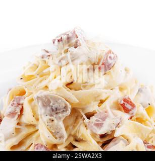 Pasta cremosa alla carbonara con prosciutto e funghi serviti su un piatto bianco Foto Stock