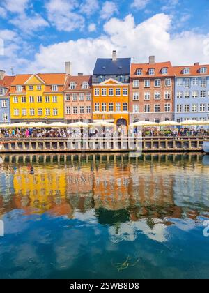 I colorati edifici sul lungomare si riflettono in acque calme sotto un cielo luminoso a Copenhagen Foto Stock