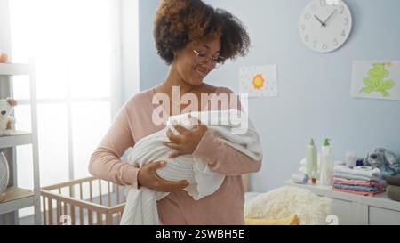 Donna sorridente amorevolmente al bambino in un'accogliente camera da letto con culla che mostra una calda atmosfera familiare e un ambiente di cura interno. Foto Stock