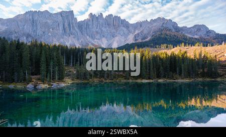 Incantevoli riflessi delle cime dolomitiche accanto a un tranquillo lago alpino all'ora d'oro Foto Stock