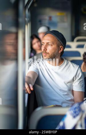 Uomo nel profondo del pensiero che guarda fuori dalla finestra del treno, pensa, lavora l'equilibrio della vita mentre va al lavoro. Foto Stock