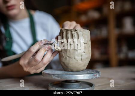 Processo di creazione della ceramica. Artista femminile che plasma e scolpisce ceramiche di argilla. Tavolo da lavoro in studio Foto Stock