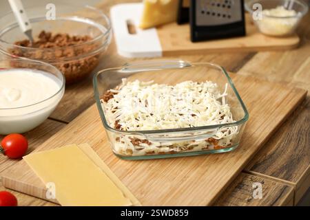 Diversi ingredienti e piatto da forno con deliziose lasagne crude sul tavolo in cucina Foto Stock