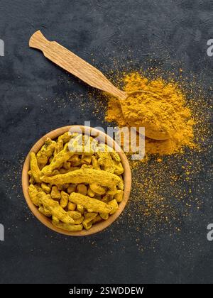 Polvere di curcuma e radici curcuma su sfondo nero Foto Stock