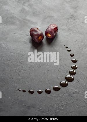 Sfondo nero Ramadan con datteri e sciroppo di datteri versati a forma di luna crescente. Foto Stock