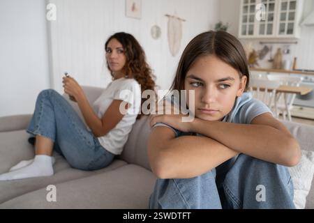 Casual preoccupata donna si siede sul divano dietro triste ragazza teen si appoggia sulle ginocchia guarda in lontananza sente Foto Stock