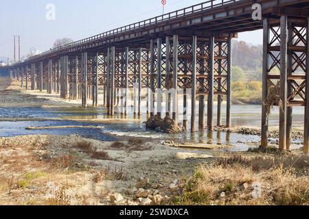 Cheongju, Corea del Sud - 12 novembre 2020: Un lungo ponte metallico color ruggine sostenuto da travi d'acciaio incrociate attraversa il fiume Mihocheon, con sig Foto Stock