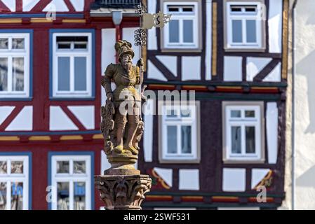 Uomo della fontana del mercato con bandiera del mercato, cavaliere, scultura in arenaria, figura della fontana al Kump, fontana medievale del mercato, alte case in legno Foto Stock