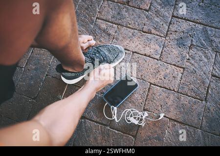 Fitness, scarpe, cravatta e telefono con uomo in città per sfide di allenamento, monitoraggio del tempo e corsa. Primo piano, maratona e salute app con persona in Foto Stock