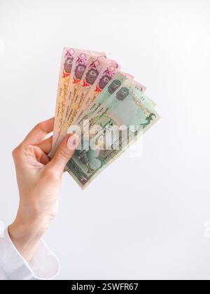 Dirham arabi banconote in mano su uno sfondo chiaro. Foto Stock