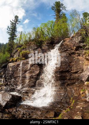 Paesaggio estivo panoramico con grande cascata verticale sulla cima della montagna al sole nel Parco Ergaki. Russia, Sayan occidentali. fa alto Foto Stock