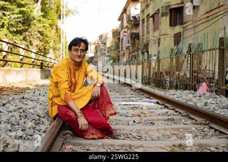 Un uomo indiano che indossa un dhoti rosso bengalese tradizionale e un kurta arancione che posa all'aperto per le strade di kolkata Foto Stock