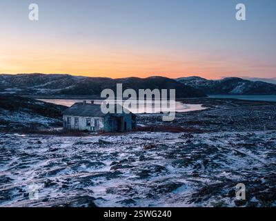 Inverno Teriberka. Paesaggio polare serale con una vecchia casa su una Foto Stock