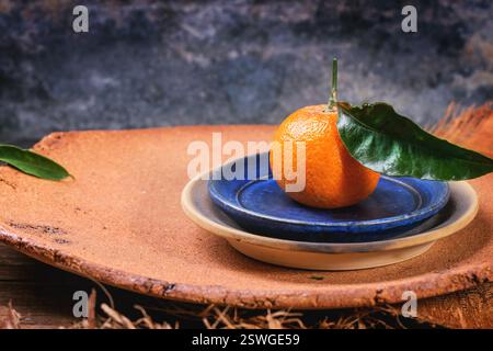 Mandarino su piatto blu Foto Stock