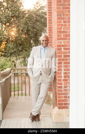 Leader sicuro in piedi accanto a un muro di mattoni al tramonto Foto Stock