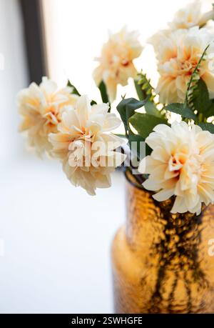 Primo piano bellissimi fiori artificiali beige in un vaso sul davanzale della finestra Foto Stock