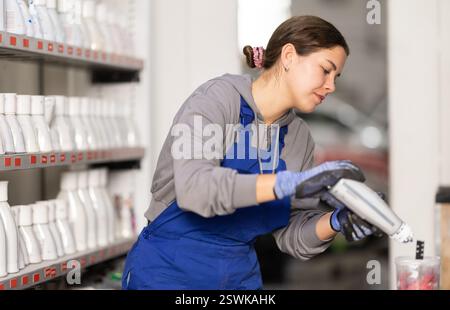 Girl Colorist seleziona il colore della vernice mescolando diversi colori per la successiva verniciatura dell'auto nel centro di assistenza auto Foto Stock