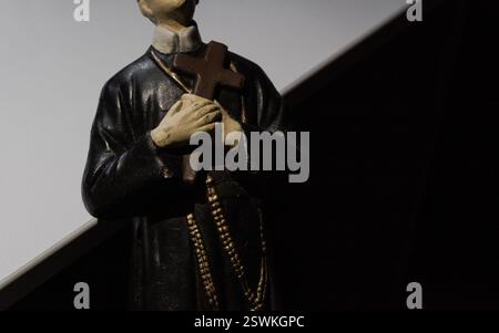 Una figura di un monaco cristiano che regge croce e perline di rosario su sfondo bianco e nero con spazio di copia Foto Stock