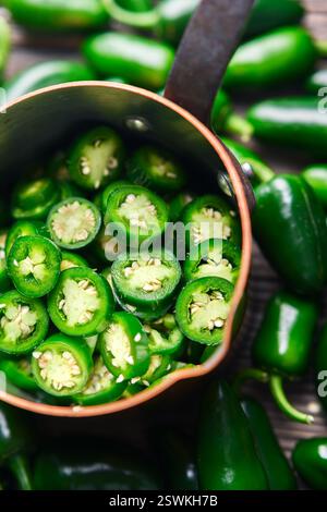 Peperoncino jalapeno messicano verde a fette in una teglia di rame da vicino. Fotografia gastronomica Foto Stock