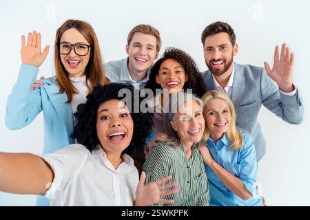 Un gruppo di professionisti che si occupano di abbigliamento da ufficio sorridenti si posa insieme su uno sfondo grigio Foto Stock