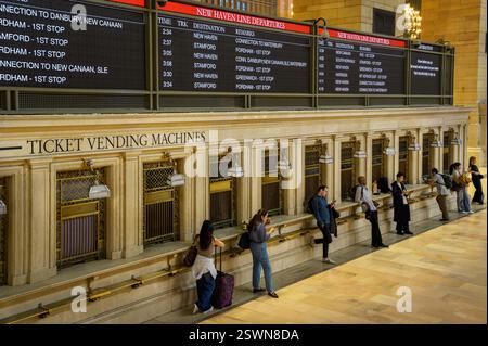 Pendolari in attesa presso distributori automatici di biglietti sotto gli orari all'interno del Grand Central Terminal, Manhattan, New York, Stati Uniti Foto Stock