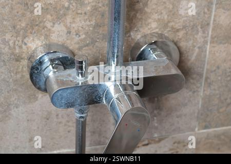 Rubinetto sporco con depositi di sale dall'acqua in bagno su moderne piastrelle scure in marmo. Pulizia e pulizia. Cura della casa e dell'ordine. Stile di vita. Foto Stock