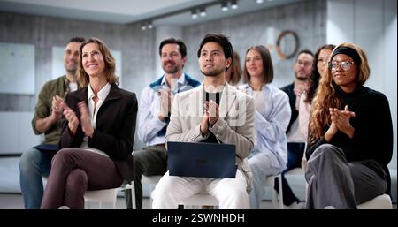 Diversi professionisti applaudono in sala conferenze dopo un seminario di lavoro di successo. Foto Stock