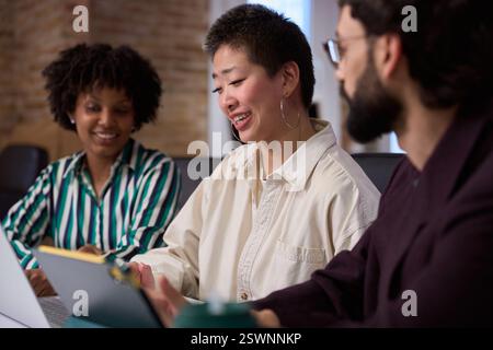 Gli uomini d'affari che lavorano insieme utilizzando un computer portatile e un tablet digitale nella sala riunioni dell'ufficio Foto Stock