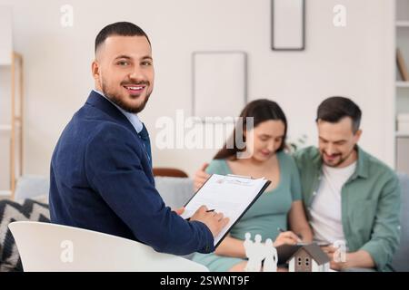 Agente immobiliare maschile con contratto di affitto della casa e coppia in ufficio Foto Stock