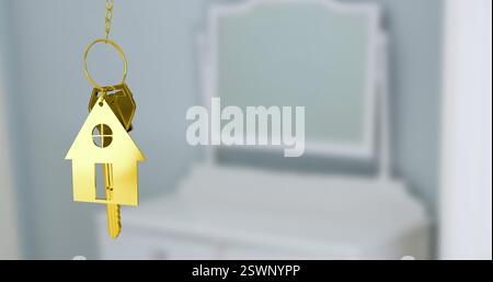 Immagine del portachiavi della casa dorata su sfondo bianco sfocato dei mobili Foto Stock