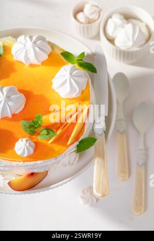 Gustosa meringa di pesca servita come dessert in primavera. Meringa di pesca con frutta e zucchero di caster. Foto Stock