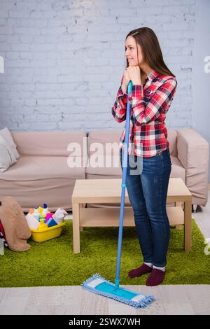 la donna lava il pavimento, tenendo il mocio in mano, in piedi nella stanza. Faccende domestiche Foto Stock
