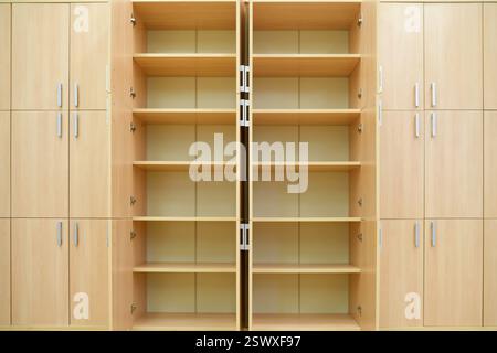 Libreria vuota in legno con porte aperte e ripiani multipli. Mobili simmetrici con maniglie in metallo in interni moderni. Archiviazione e organi Foto Stock