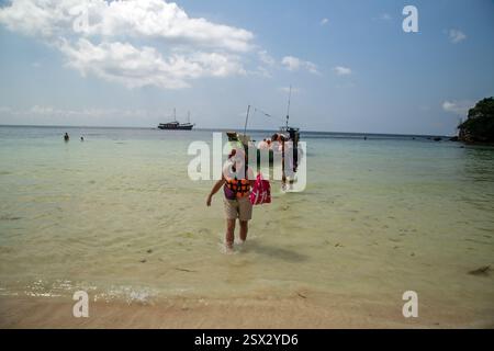Koh Samui, Thailandia, 6 febbraio 2025, i turisti sbarcano da una barca a coda lunga che li portava più vicino a riva dalla piccola nave su cui erano Foto Stock