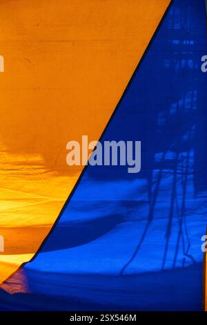 Texture colorata di una vecchia tenda da circo che forma figure geometriche blu e gialle. Composizione di strutture astratte su tela Foto Stock