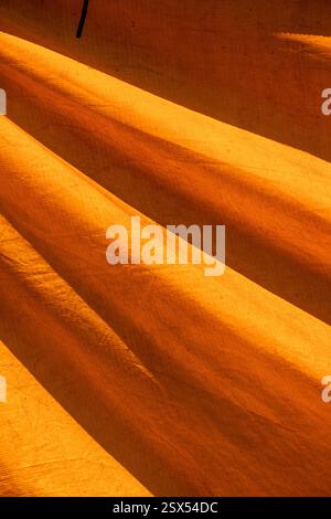 Texture colorata di una vecchia tenda da circo che forma figure grafiche gialle e arance. Composizione di strutture astratte su tela Foto Stock
