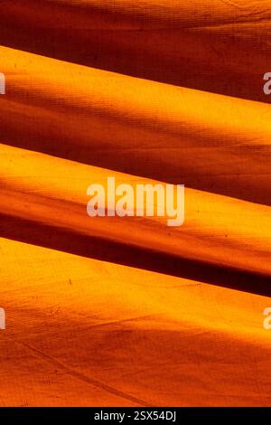 Texture colorata di una vecchia tenda da circo che forma figure grafiche gialle e arance. Composizione di strutture astratte su tela Foto Stock