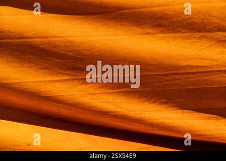 Texture colorata di una vecchia tenda da circo che forma figure grafiche gialle e arance. Composizione di strutture astratte su tela Foto Stock