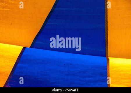 Texture colorata di una vecchia tenda da circo che forma figure geometriche blu e gialle. Composizione di strutture astratte su tela Foto Stock