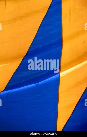 Texture colorata di una vecchia tenda da circo che forma figure geometriche blu e gialle. Composizione di strutture astratte su tela Foto Stock
