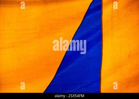 Texture colorata di una vecchia tenda da circo che forma figure geometriche blu e gialle. Composizione di strutture astratte su tela Foto Stock