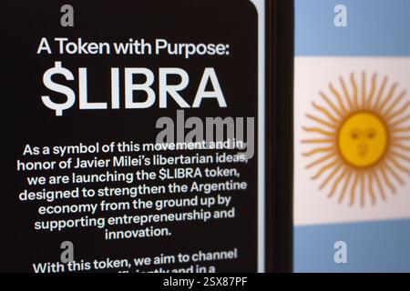 Smartphone che visualizza informazioni sul gettone $LIBRA, legato alle idee libertarie e all’economia argentina, con la bandiera argentina sullo sfondo. Foto Stock