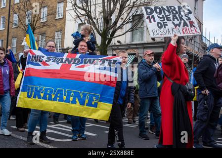 Londra, Regno Unito. 22 febbraio 2025. Una famiglia detiene una mezza Union Jack e una metà bandiera Ucraina. Dice "siamo con l'Ucraina” durante la manifestazione. Centinaia di ucraini e sostenitori si sono riuniti presso la statua di San Volodymyr. Solo due giorni prima del terzo anniversario dell'invasione russa su vasta scala in Ucraina. I manifestanti marciarono dal Monumento a San Volodymyr il grande all'ambasciata russa. (Foto di Krisztian Elek/SOPA Images/Sipa USA) credito: SIPA USA/Alamy Live News Foto Stock