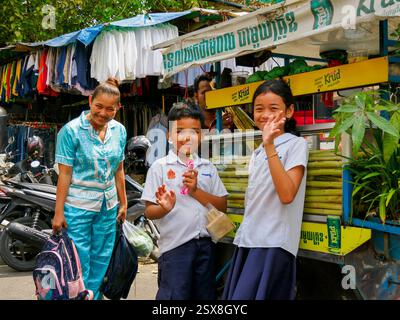 La madre porta i suoi figli a fare shopping nel mercato all'aperto di Phnom Penh Foto Stock