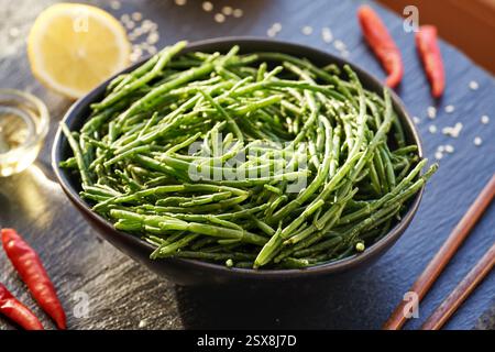 Alghe verdi di Salicornia in un recipiente con limone, semi di sesamo e peperoncino Foto Stock